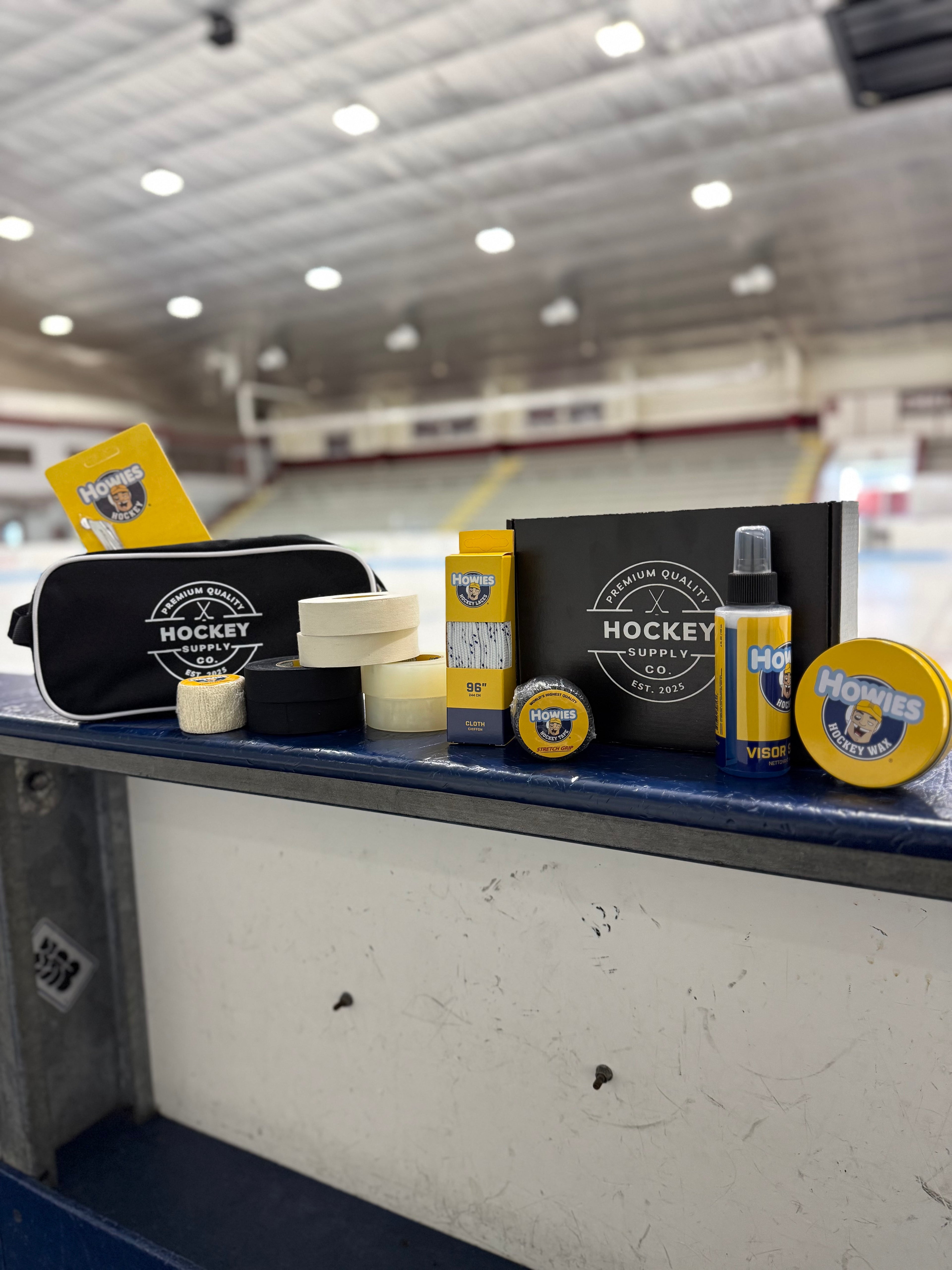 Hockey supply items including a visor, towels, and bottles on a counter with an indoor hockey rink background.